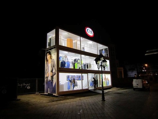 Pop-up store installé dans une structure vitrée, photographié de nuit